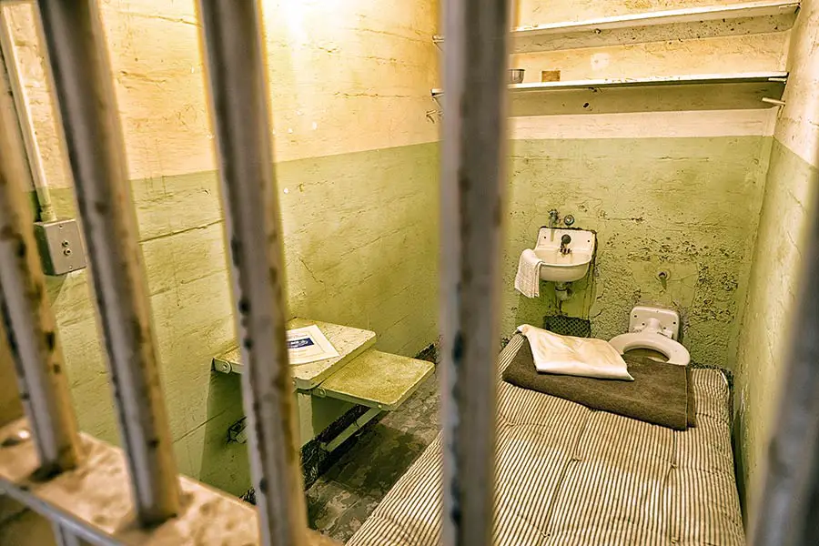 Looking through the bars at a small Alcatraz prison cell