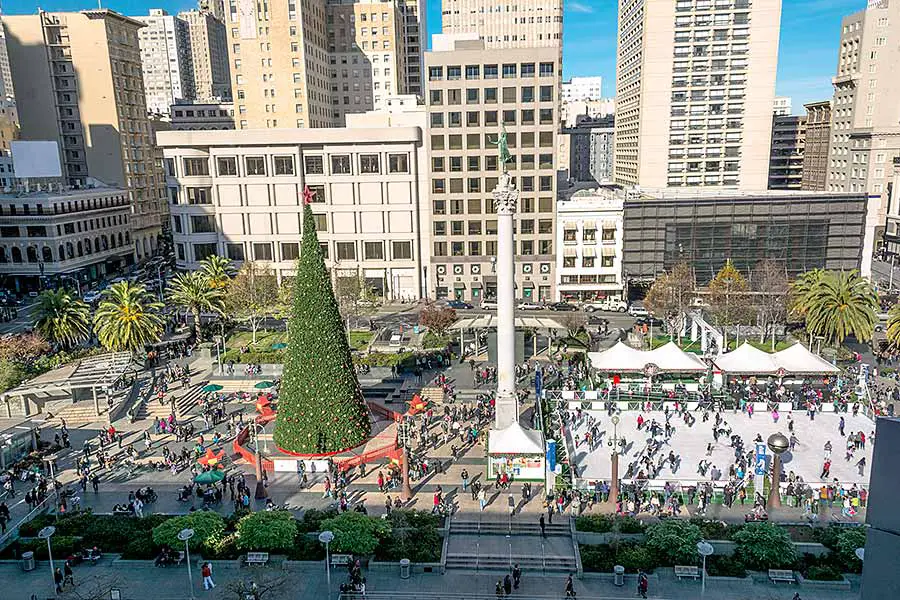 Christmas tree surrounded with people, city skyscrapers in background