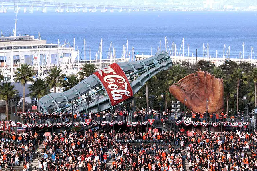 Baseball fans sitting in front of giant coke bottle and ball glove