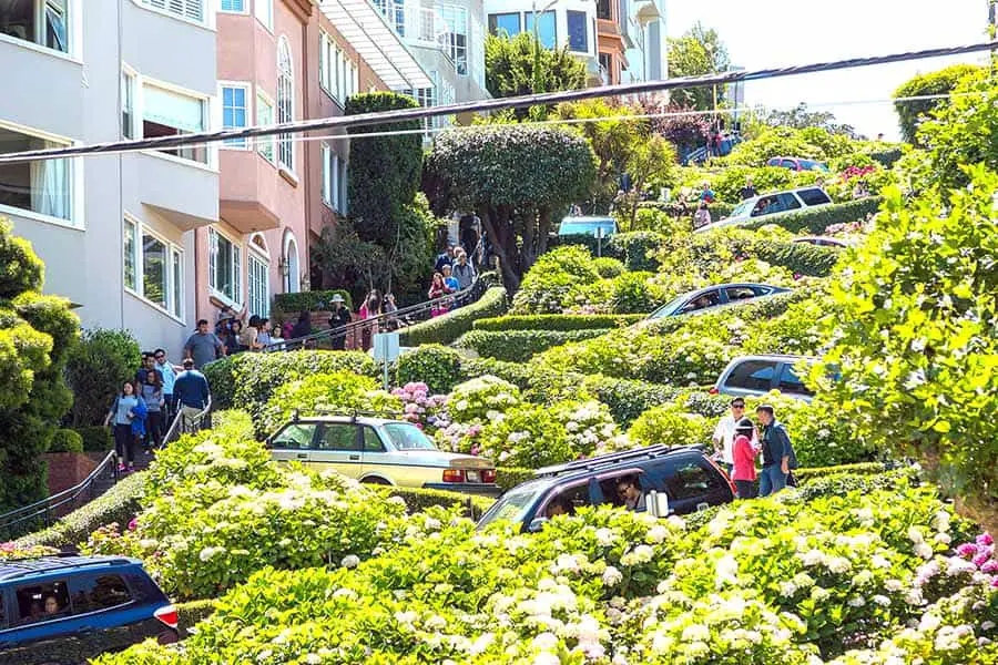 Cars driving down curvy Lombard Street, tourists watching