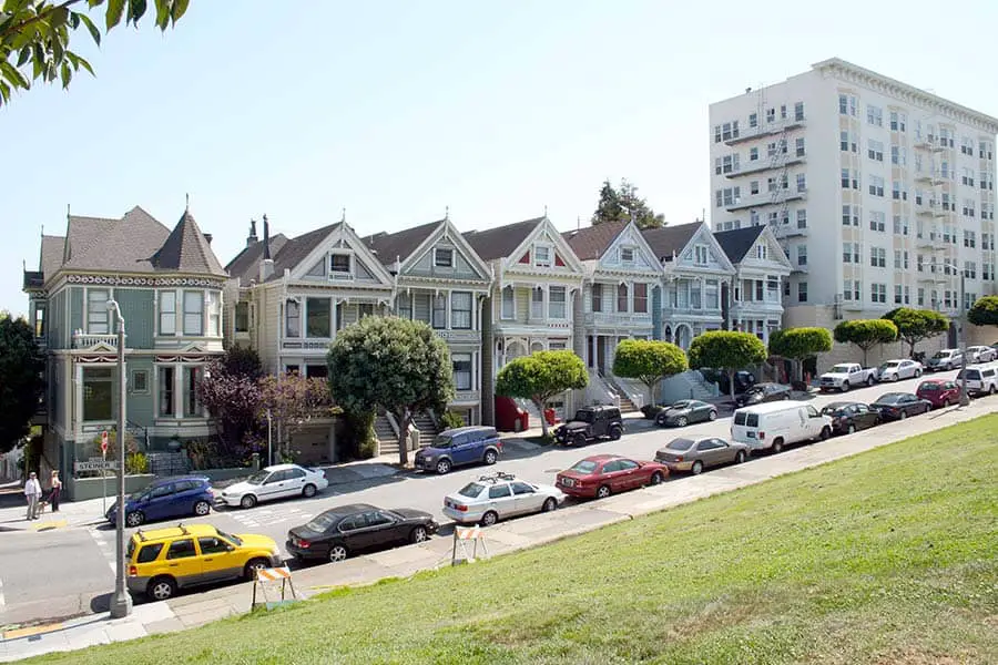 Colorful houses with cars parked along street