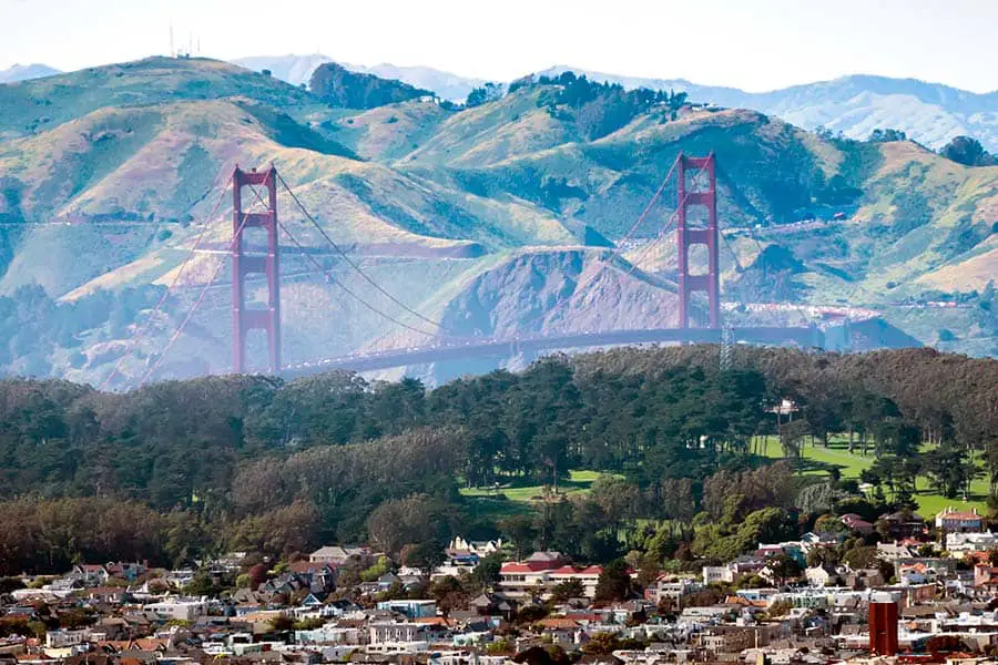 Golden Gate Bridge with mountains in the background and buildings in foreground
