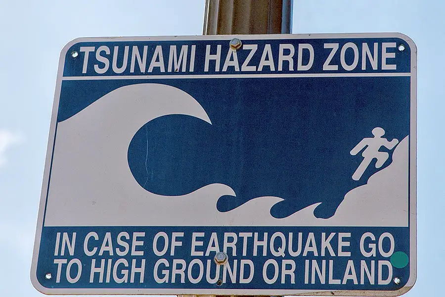 Blue and white sign with tsunami zone warning
