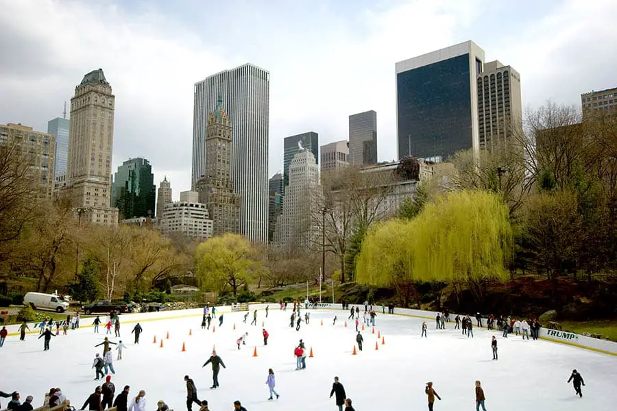 Skaters at Central Park outdoor ice rink, New York City skyscrapers in background