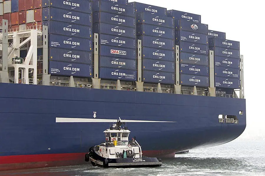 Tugboat pushing a large container ship