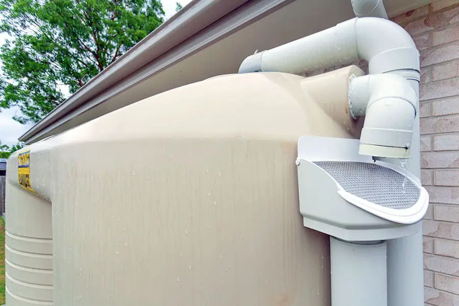 Plastic pipe connected to house eaves used to collect rainwater and store it in tank