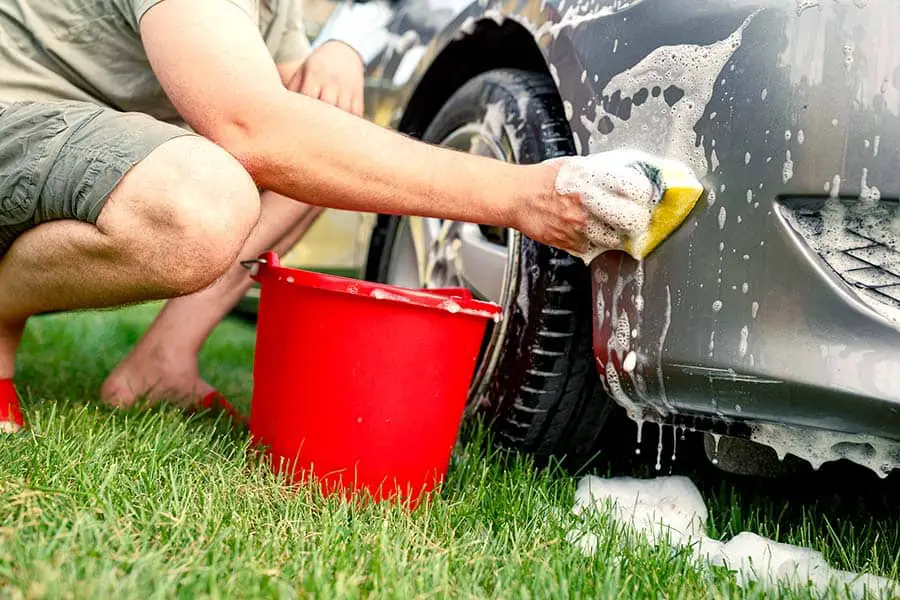 Man with red bucket washing his car