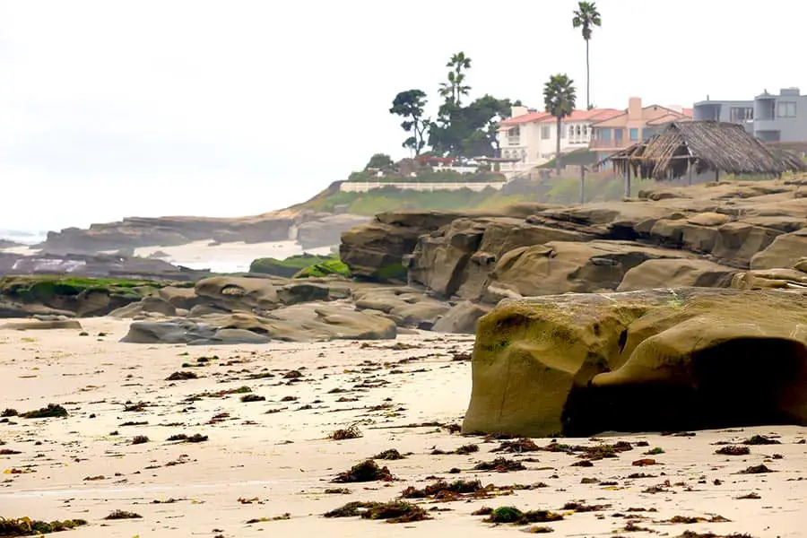 Sandy beach and large rocks, houses in background